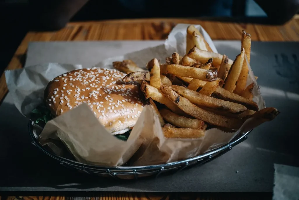 Burger and fries served in a paper-lined basket on a wooden table
