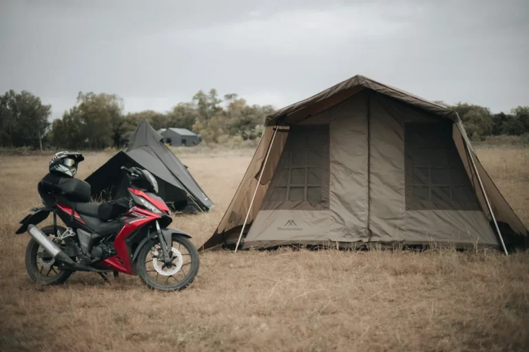 Sport motorcycle parked next to canvas camping tents in a grassy field
