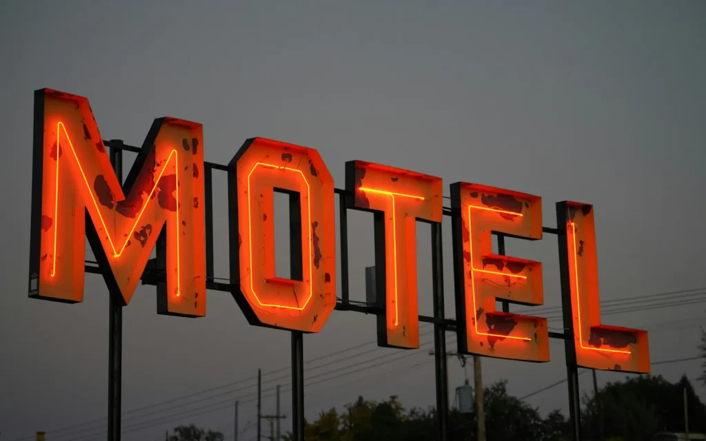 Big orange neon MOTEL letters glowing against a dusk sky