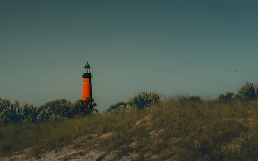 Ponce de Leon Inlet Lighthouse rising above palmetto-covered dunes at dusk, south of Daytona Beach, FL