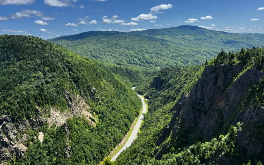 Two-lane highway winding through a forested mountain notch in northern New Hampshire in summer