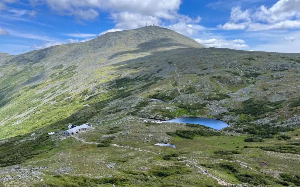 Summit of Mount Washington, NH above green alpine slopes and the Lakes of the Clouds hut