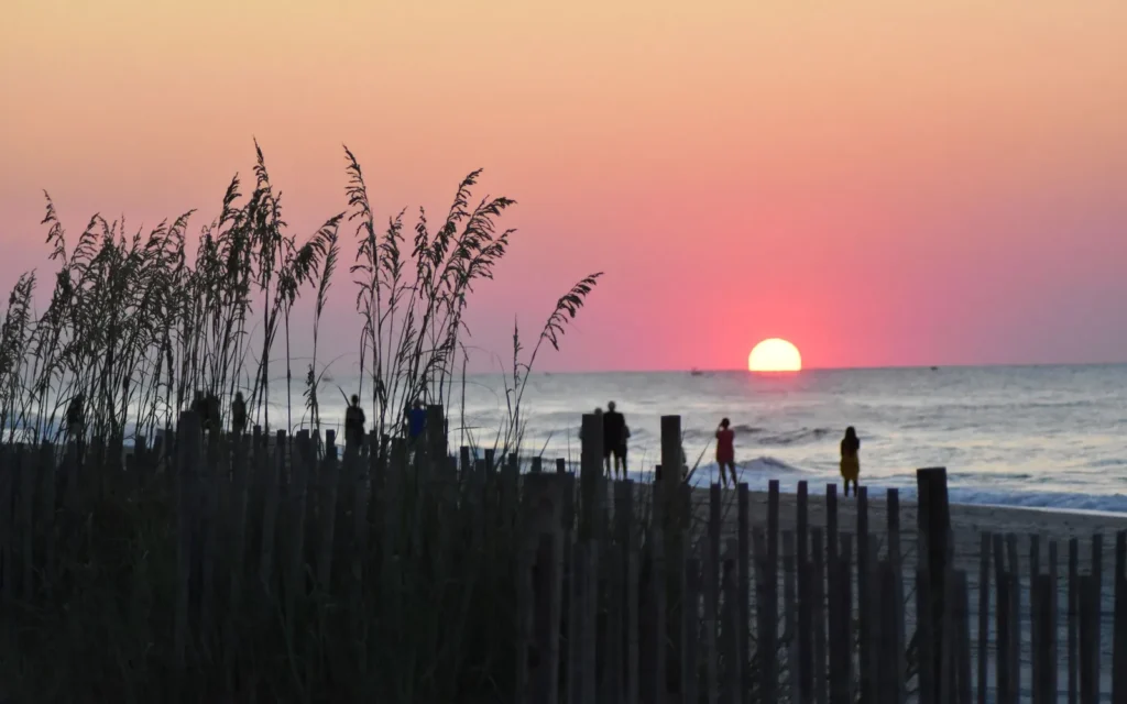 Sunrise over the Atlantic at Myrtle Beach, SC, seen through sea oats and a dune fence