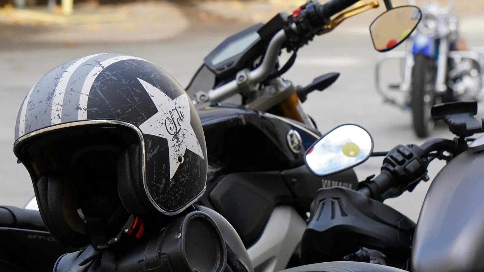 Open-face helmet resting on a motorcycle's handlebars, more bikes parked behind