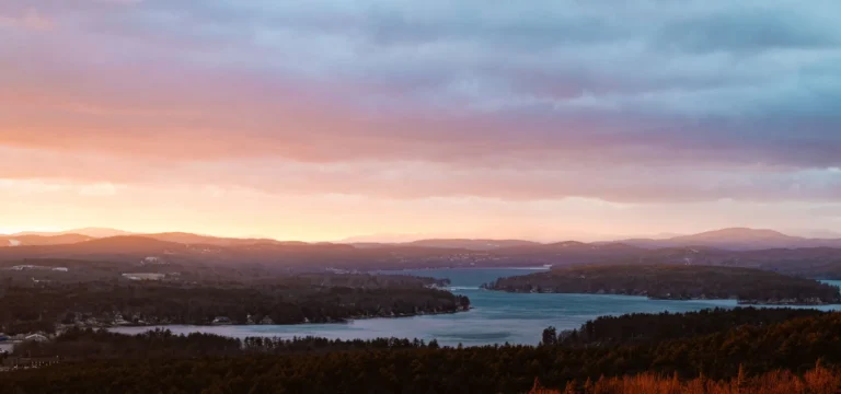 Sunset over Lake Winnipesaukee and the hills around Gilford, New Hampshire, the cover photo of our Laconia Motorcycle Week guide