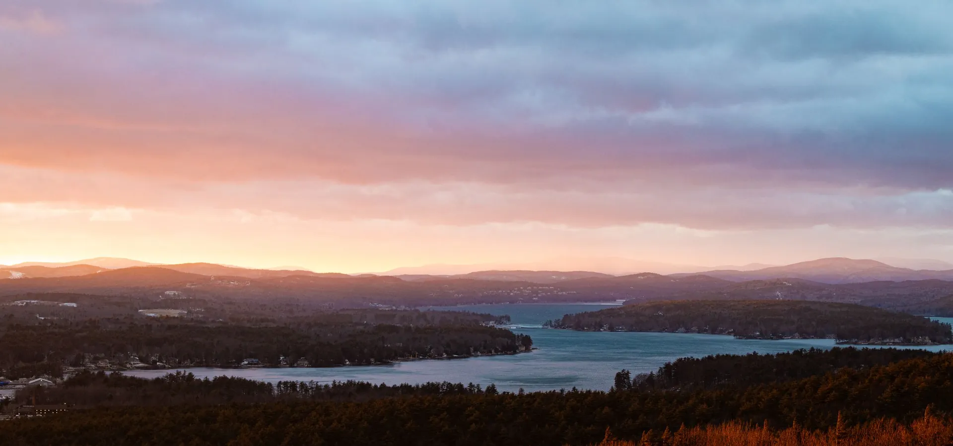 Sunset over Lake Winnipesaukee and the hills around Gilford, New Hampshire, the cover photo of our Laconia Motorcycle Week guide