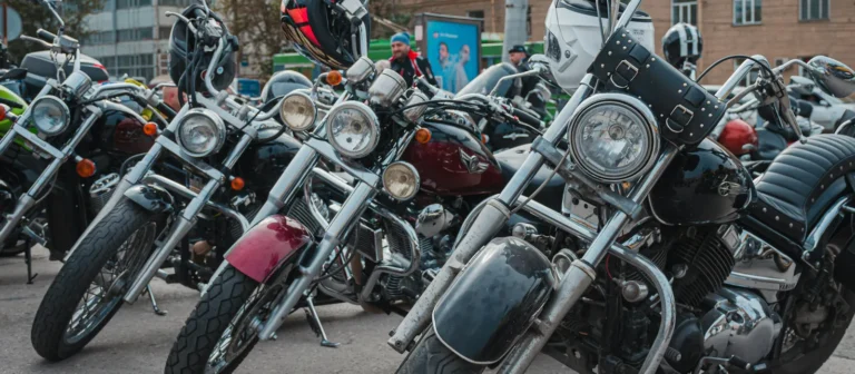 Rows of chrome cruiser motorcycles parked side by side at a rally