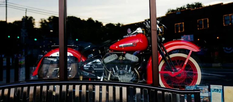 Red vintage motorcycle on display behind a shop window at dusk