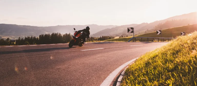 Motorcyclist leaning into a curve on an open road at golden hour