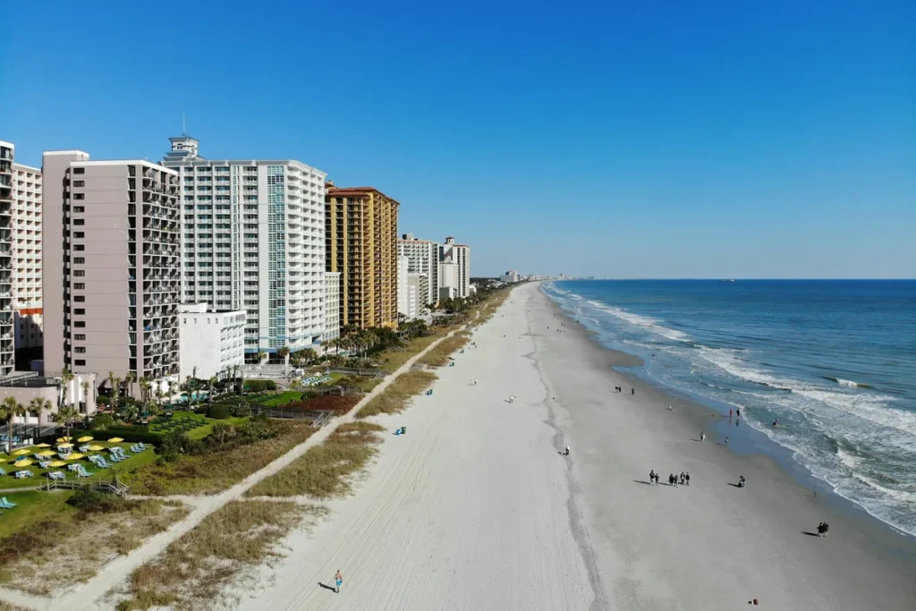 Row of oceanfront hotel towers lining a wide sandy beach
