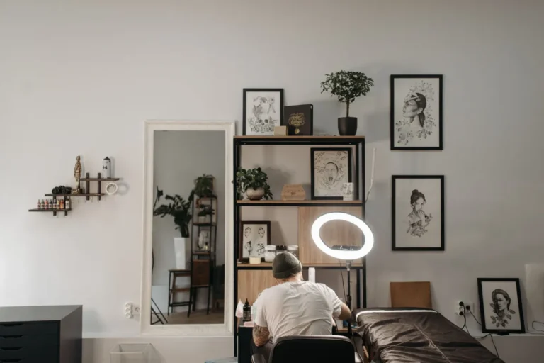 Bright tattoo studio with framed artwork, a ring light and a client bed